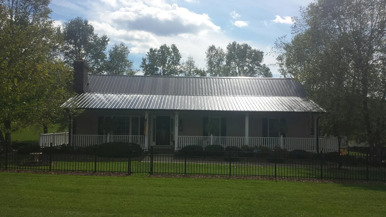 Gray metal roof on a brick ranch with a full width front porch — Gutter Guard Installation work by our crew in Dennison