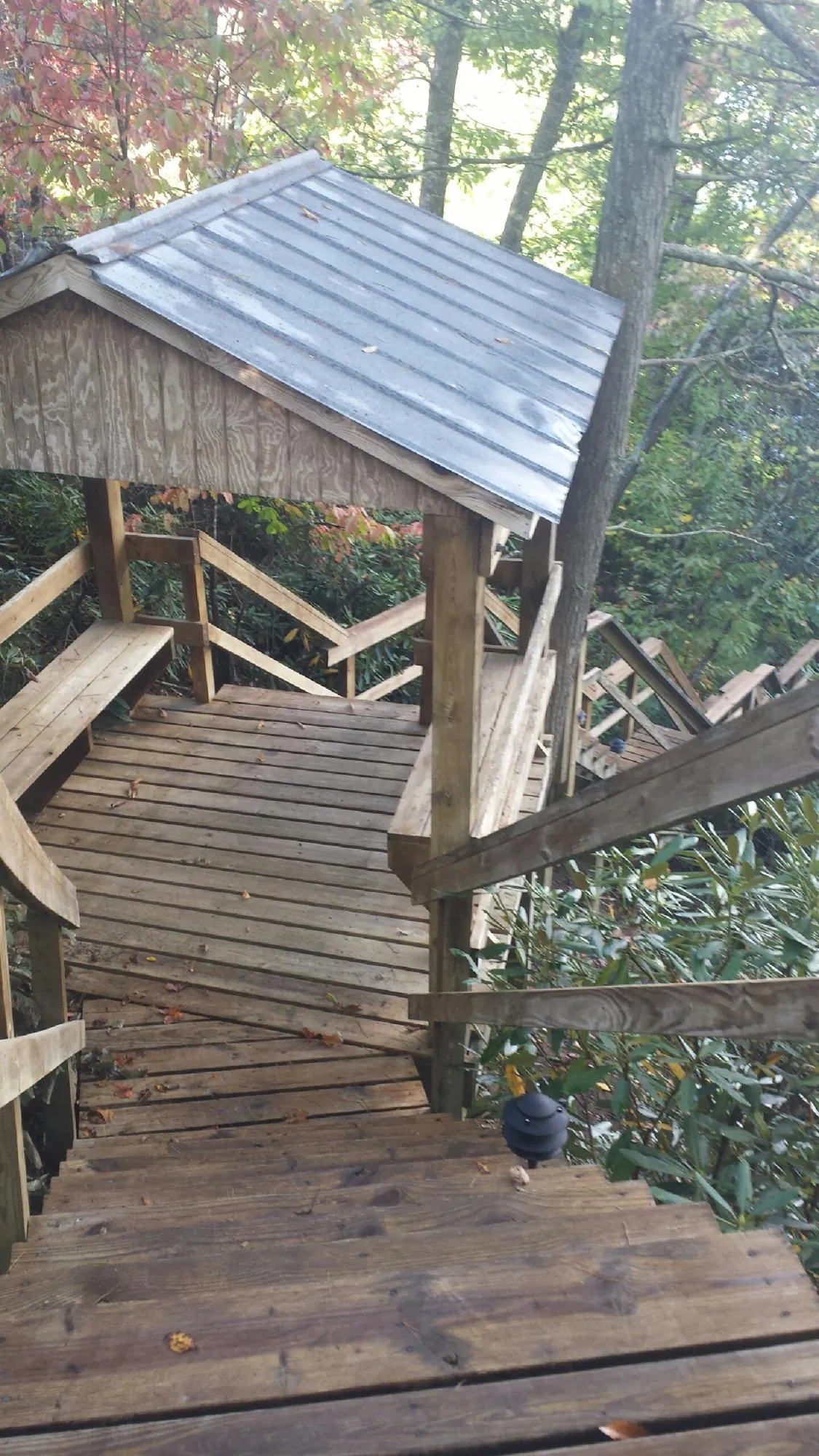 Metal roofed shelter over wooden steps on a wooded walkway — Skylight Repair & Installation work by our crew in Dennison