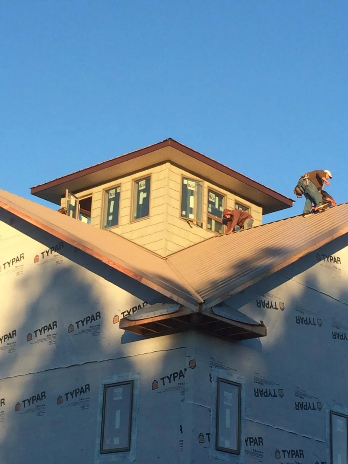 Roofers working around a rooftop cupola on a new metal roof at sunset — Roof Waterproofing in Dennison by Roofing Brothers